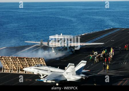 Eine E-2C Hawkeye startet aus einer von vier Dampfgetriebenen katapulten als F/A-18 Hornet Taxis in Position auf der viel befahrenen Flight Deck der USS Nimitz (CVN 68) zum Betrieb in den Pazifischen Ozean am Dez. 2, 2004. Der Nimitz Highway ist die Durchführung einer Composite Trainingsgerät Übung vor der Küste von Südkalifornien. Die Hawkeye ist die Fluggesellschaft Airborne Early Warning Squadron 117 zugeordnet. Stockfoto