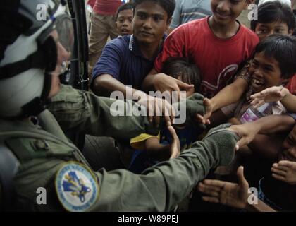 Ein U.S. Navy aircrewman zu Hubschrauber Anti-Submarine Squadron 2 zugeordneten schüttelt die Hände der lokalen Bürger nach Lieferung von Nahrung und Wasser in ihr Dorf in Indonesien auf Jan. 6, 2005. Der Flugzeugträger USS Abraham Lincoln (CVN 72) und seine eingeschifft Carrier Air Wing 2 2 sind die im Indischen Ozean vor der Küste von Indonesien und Thailand zur Unterstützung der Operation Unified Hilfe. Stockfoto