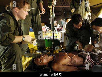 Marine Petty Officer 1st class Rebecca McClung (links) und Chief Petty Officer Jim Jones (rechts) neigen zu einem verletzten indonesischen Mann, medizinisch aus einem Dorf an der Küste auf der Insel Sumatra, Indonesien, Jan. 3, 2005 evakuiert wurde. Medizinische Teams aus dem Flugzeugträger USS Abraham Lincoln (CVN 72) und der Internationalen Organisation für Migration haben eine Triage Aufstellungsort auf Sultan Iskandar Muda Air Force Base, in Banda Aceh, Sumatra. Die beiden Teams arbeiten gemeinsam mit Mitgliedern der Australischen Luftwaffe erste medizinische Versorgung für die Opfer des Tsunami zu bieten betroffenen Küstenregionen. T Stockfoto