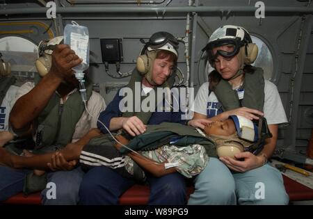 U.S. Navy Nurse Cmdr. Karen McDonald (Mitte) und eine Krankenschwester aus der Organisation Projekt HOFFNUNG (rechts) Komfort eines Jungen leiden unter einem perforierten Anlage an Bord eines US-Hubschraubers in Sumatra, Indonesien, Jan. 6, 2005. Der Junge und sein Vater (links) wird an das Krankenhaus ship USNS Mercy (T-AH 19) für ärztliche Behandlung transportiert. Barmherzigkeit ist derzeit vor der Küste von Banda Aceh, Sumatra, Indonesien, medizinische Hilfe und Katastrophenhilfe für die Menschen in Indonesien nach dem verheerenden Tsunami in Südostasien am Dez. 26, 2004 Hit betroffen sind. McDonald ist der Barmherzigkeit assistant di Stockfoto