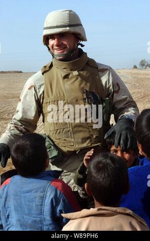 Marine Ensign Majid Awad spielt mit lokalen irakische Kinder in Najaf, Irak, Jan. 24, 2005. Awad und andere Navy Seabees der Naval Mobile Konstruktion Bataillon 7 Arbeiten mit Bewohner einer kleinen Beduinendorf am Stadtrand von Nadschaf eine Schule zu bauen und Verbesserungen in das Dorf, Wasser, Strom und sanitäre Einrichtungen. Awad ist aus Bahrain. Stockfoto