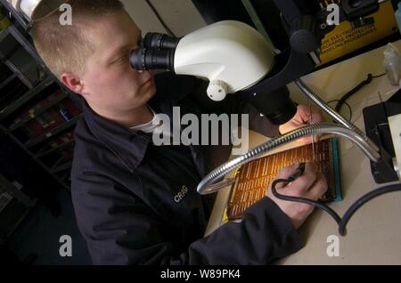 Petty Officer 2nd class Robert Craig Reparaturen ein Mikro-LS-Karte in der Avionik Arbeitsplatz an Bord der USS Kitty Hawk (CV 63) als das Schiff im Pazifik am 5. März 2005 arbeitet. Craig ist ein Navy Aviation Electronics Techniker der Flugzeugträger Flugzeug Intermediate Maintenance Abteilung zugewiesen. Stockfoto