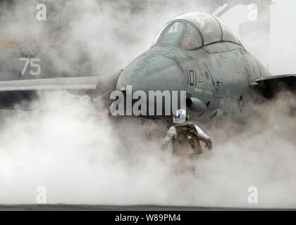 Dampf aus dem katapult Umschläge ein Navy F-14 Tomcat als die Crew bereitet Sie für den Start von Flight Deck des Flugzeugträgers USS Harry S. Truman (CVN 75) am 13.02.22, 2005, während der Fahrt im Persischen Golf. Die Truman Strike Group und Carrier Air Wing 3 leitend sind enge Luftunterstützung, Intelligence, Surveillance und Reconnaissance Missionen über den Irak. Der Tomcat wird auf Kämpfer angefügte Squadron 32 der Naval Air Station Oceana, Virginia. Stockfoto