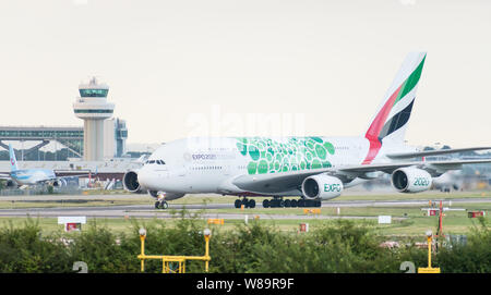 Eine Emirates Airlines Airbus A 380-861 in eingerichtete Green Expo livery 2020 erlischt die Start- und Landebahn vor der Air traffic control tower nach der Landung. Stockfoto