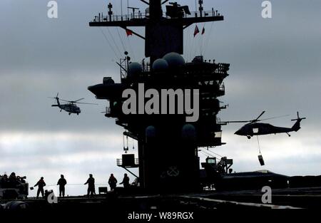 Navy MH-60S Seahawk Hubschrauber Luftbrücke Munition vom Flugzeugträger USS Nimitz (CVN 68) an die militärischen Sealift Command schnell Combat support ship USNS Brücke (T-AOE 10) wie die beiden Schiffe in den Pazifischen Ozean am 10.02.2006. Stockfoto