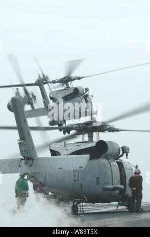 Als einer MH-60S Seahawk löst ein weiterer Hubschrauber bereitet aus dem Flight Deck des Flugzeugträgers USS Kitty Hawk (CV 63) Bei Flugbetrieb in den Pazifischen Ozean am 29. Mai 2006 zu starten. Stockfoto