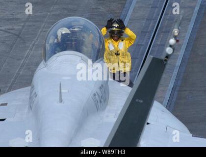 Ein Navy Flight Deck crewman verwendet Hand signalisiert der Pilot einer F-18 Hornet a für starten Sie aus dem Flight Deck des Flugzeugträgers USS Dwight D. Eisenhower (CVN 69) am Okt. 23, 2006 zu katapultieren. Eisenhower ist zur Unterstützung der Sicherheit im Seeverkehr im Einsatz sind. Stockfoto