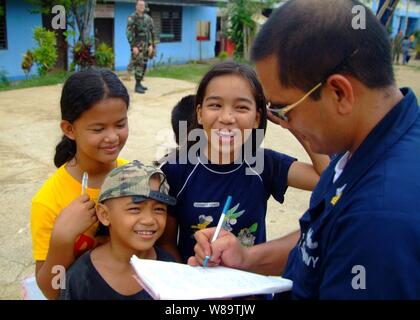 U.S. Navy Petty Officer 1st Class Allen Borromeo Yabut (rechts) Zeichen, seinen Namen und seine e-mail Adresse, die in den Notebooks von Pasobolong Grundschüler in Zamboanga, Philippinen, am Okt. 26, 2006. Segler aus den Amphibischen dock Landung Schiff USS Harpers Ferry (LSD 49) besucht die Schule mit Joint Special Operations Task Force-Philippines als Teil einer Dienstleistung Projekt verarmten Gebieten in den Gemeinschaften von den Philippinen zu unterstützen. Stockfoto