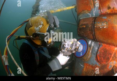 U.S. Navy Diver Petty Officer 1st Class Josh Moore nutzt eine Schleifscheibe, um eine Reparatur Patch auf dem versunkenen Bug der USS Ogden LPD (5) während des Aufenthaltes des Schiffes im Hafen am Naval Base San Diego, Calif., Jan. 4, 2007. Moore ist Mitglied der Schweißen unter Wasser Team die Region Südwest Maintenance Center Dive Schließfach. Stockfoto