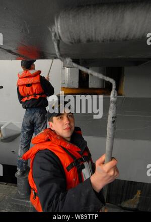 U.S. Navy Seaman Harold G. Lanham gilt Haze-graue Farbe an einem Flugzeug Aufzug auf dem Flugzeugträger USS Abraham Lincoln (CVN-72) im Marinestützpunkt Kitsap Bremerton, Washington, am 14. März 2007. Lincoln ist das Nachbearbeiten der letzten Phase seiner Trockendock inkrementelle Verfügbarkeit, der das Schiff für die Rückkehr zur vollen Betriebsfähigkeit vorbereitet, geplant. Stockfoto