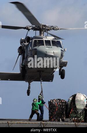 Us-Marine Seeleute aus dem usns Brücke (T-AOE 10) Haken oben Ladung zu einem MH-60S Knight Hawk Hubschrauber für den Transport der Nimitz-Klasse Flugzeugträger USS John C Stennis (CVN 74) während einer Auffüllung auf See, während im Arabischen Meer am 15. Mai 2007. Stockfoto