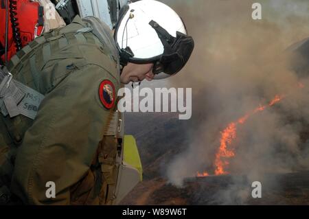 U.S. Navy Chief Aviation Electronics Technician Rexford Sackett blickt auf Meilen von verbrannten Gelände in San Diego, Calif., wie er und die anderen Matrosen bereiten Wasser auf der Flamme von einem MH-60S Seahawk Hubschrauber am Okt. 23, 2007 zu fallen. Sackett ist zu Hubschrauber Meer Combat Squadron 85 zugeordnet sind, der Hubschrauber speziell mit einem 420-Liter Löschmittel Trog benutzt, um Wasser auf die laufenden San Diego Feuer Katastrophe dump ausgestattet. Die Flamme hat bereits gezwungen, mehr als eine Million Menschen aus ihren Häusern. Stockfoto