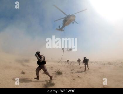 Us-Marines laufen durch eine Wolke von Staub, wie sie der Praxis schnell Abseilen von einem MH-60S Knight Hawk Hubschrauber während einer Krise Antwort Übung in Bahrain an November 5, 2007. Marines 4 Platoon angebracht, 2. Flotte Antiterrorism Security Team sind die Durchführung der Übung Antwort auf die Anfrage eines Host Nation für die Hilfe in einer Zeit der Krise zu verbessern. Stockfoto