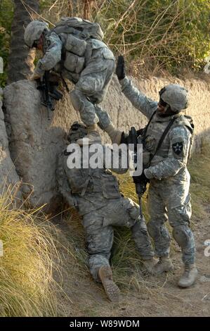 Ein Soldat der US-Armee erhält eine Erhöhung in einer Wand von seinen Kameraden, wie Sie eine Mission in Diyala, Irak, am 13.02.2008. Soldaten aus dem zweiten Bataillon, 12 Artillerie Regiment helfen zurück irakischen Vertriebenen in ihre Häuser. Stockfoto