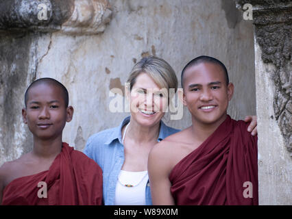 Eine glückliche Frau und zwei jungen Burmesischen buddhistischen Mönche in der Dhammayangyi Tempel in Bagan Myanmar lächelnd in die Kamera die Frau losgelassen wird. Stockfoto