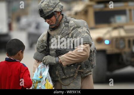 Us Air Force Airman 1st Class Justin Iverson, um das Ablösen 3, 732 . Expeditionary Sicherheitskräfte Squadron, zu der 1. Brigade Combat Team angeschlossen, 4 Infanterie Division, Hände, die Süßigkeit zu irakischen Kinder während einer Patrouille im doura Stadtteil von Bagdad, Irak, an November 22, 2008. Stockfoto