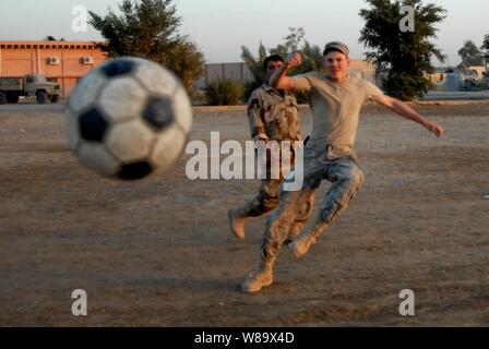 Us-Armee Pfc. Casey Wailes, von der 1. Staffel, 10 Golgatha Regiment, 2nd Brigade Combat Team, 4 Infanterie Division löscht den Ball bei einem Fußballspiel mit der irakische Soldaten in Mahawil, Irak, Dez. 14, 2008. Stockfoto