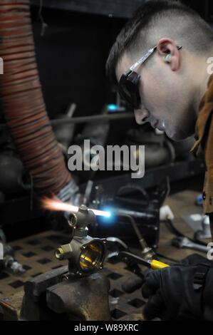 U.S. Navy Petty Officer 3. Klasse Carl Thompson ändert eine Dusche Mixer mit einem Autogen Fackel in der Pipe Shop an Bord der Flugzeugträger USS Ronald Reagan (CVN 76), während das Schiff im Golf von Oman unterwegs am 1. August 2009. Thompson ist als Rumpf Wartungstechniker, die für die Erhaltung der Rümpfe, Armaturen, Rohrleitungen und Anlagen zuständig ist, zugewiesen. Der Träger ist für die US-Flotte 5 Bereich der Operationen eingesetzt. Stockfoto