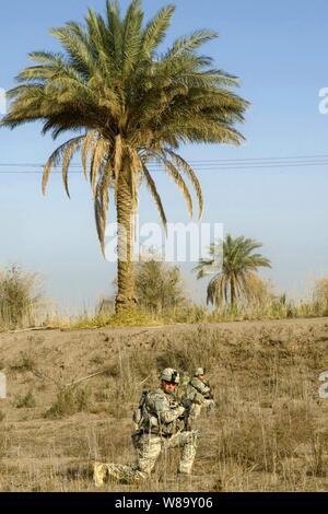 Us-Armee Soldaten zu Bravo Unternehmen angeschlossen, 5 Bataillon, 20 Infanterie Regiment, 3 Stryker Brigade Combat Team, 2 Infanterie Division knien während der Durchführung einer Patrouille in Naquib, Irak, an November 8, 2009. Die Soldaten patrouillieren der Bereich offene Felder auf Anzeichen von vermuteten Waffen Caches zu suchen. Stockfoto