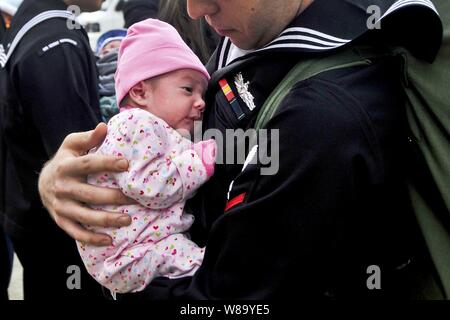 U.S. Navy Petty Officer 3rd Class Matthew Sandlin hält seine neugeborene Tochter zum ersten Mal, nachdem er unterwegs für sechs Monate an Bord der Flugzeugträger USS George Washington (CVN 73) im Pazifischen Ozean in Yokosuka, Japan, November 1, 2010. Sandlin wird als Maschinist mate zugeordnet. Stockfoto