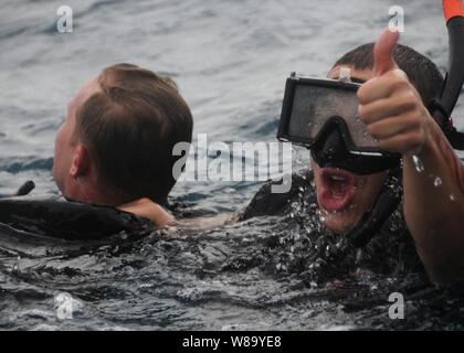 U.S. Navy Petty Officer 3. Klasse Andres Acosta (rechts) Signale an ein Crew während der Rettung von Petty Officer 1st Class Kurt Bartholomai während der Suche und Rettung Schwimmer Ausbildung in der Javasee an November 8, 2010. Acosta ist die Amphibisches Schiff USS Essex (LL 2), die Teil der dauerhaft Vorwärts zugeordnet - bereitgestellt von Essex Amphibious Ready Gruppe auf Patrouille im westlichen Pazifischen Ozean. Stockfoto