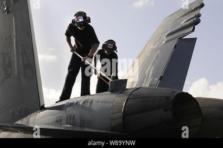 Airman rekrutieren Teddy Frisby (links) und Flieger Lehrling Kevin Dwyer, sowohl für Strike Fighter Squadron 113 zugeordnet, waschen eine F/A-18C Hornet auf dem Flugdeck der Flugzeugträger USS Carl Vinson (CVN 70) im Arabischen Meer am 13.02.11., 2011. Die Carl Vinson Carrier Strike Group bereitgestellt ist die Maritime Security Operations und Theater Sicherheit Zusammenarbeit in den USA 5 Flotte Verantwortungsbereich. Stockfoto