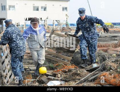 Chief Petty Officer Kyle Wilkinson (rechts), von Baldwinsville, N.Y., zu Naval Air Facility Misawa zugeordnet, hilft Ablagerungen während einer reinigungbemühung am Misawa Fischereihafen am 14. März 2011 entfernen. Mehr als 90 Matrosen von Naval Air Facility Misawa freiwillig helfen Misawa Stadt Mitarbeiter und Mitglieder der Gemeinschaft beginnen, nach einem Erdbeben und Tsunami zu reinigen. Stockfoto