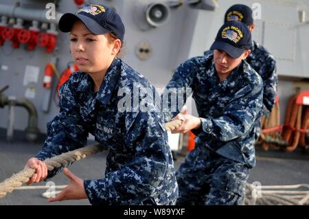 Seaman Erika Berry und Seemann Robert Toohey hebe eine Linie im Meer und anker detail an Bord der geführte Anti-raketen-Zerstörer USS Decatur (DDG73) in der Nähe von Mina Salman, Bahrain, am 9. März 2011. Die Decatur auf Routine Implementierung Durchführung Maritime Security Operations in den USA 5 Flotte Verantwortungsbereich. Stockfoto