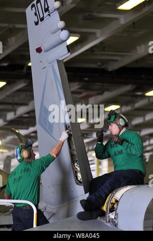 Airman Deutsche Alulzo (links) Streifen Dichtmittel aus dem Ruder als Flieger Kells Dekan installiert ein Ruder Lager während der Phase einer Inspektion an einer F/A-18C Hornet aircraft an Bord der Flugzeugträger USS Ronald Reagan (CVN 76) im Pazifischen Ozean am 25. April 2011. Stockfoto