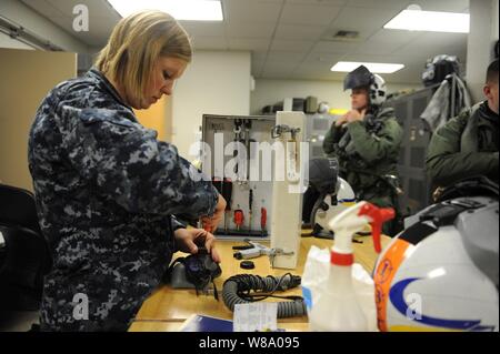 U.S. Navy Airman Jessica Tescher (links), einen Fallschirm Rigger, führt eine monatliche Wartung prüfen, auf der ein Pilot Helm während der Übung der nördlichen Flanke am Joint Base Elmendorf-Richardson, Alaska, am 16. Juni 2011. Nördlichen Rand ist eine jährliche gemeinsame Ausbildung Übung für militärische und zivile Reaktion und Koordination Fähigkeiten, während gleichzeitig das Kommando, Kontrolle und Kommunikation Beziehungen mit gemeinsamen Aktionen zu testen. Stockfoto