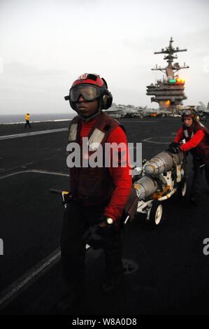 Petty Officer 3rd Class Damion Ferguson (links) und Petty Officer 2nd class Christopher Bowman transport Sprengkörper auf dem Flugdeck der Flugzeugträger USS George H.W. Bush (CVN 77) im Arabischen Meer. Am 18. Juli 2011. Die George H.W. Bush wird eingesetzt zur Unterstützung Maritime Security Operations und Theater Sicherheit Zusammenarbeit in den USA 5 Flotte Verantwortungsbereich auf seinen ersten Einsatz. Stockfoto