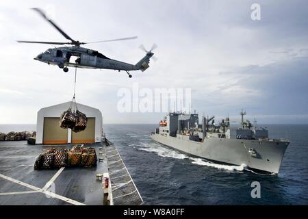 Ein MH-60S Knight Hawk Hubschrauber Transporte Fracht von der USNS Comfort auf die usns Lewis und Clark während einer Auffüllung Mission unterwegs in den Pazifischen Ozean am 26. Juli 2011. Stockfoto