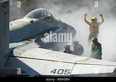 U.S. Navy Petty Officer 3rd Class Eric Welsh leitet eine F/A-18C Hornet auf dem Bug Katapulte für Produkteinführung auf dem Flugdeck an Bord der Flugzeugträger USS Carl Vinson im Persischen Golf am 5. März 2012. Walisisch ist eine Aviation Bootsmann mate, Handling. Stockfoto