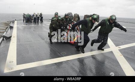 Us-Marine Seeleute während einer vertikalen Auffüllung im Japanischen Meer zugewiesen Hubschrauber Anti-Submarine Squadron Licht 51 Paletten bewegen Sie das Flight Deck der USA 7 Flotte Befehl Schiff USS Blue Ridge (LCC 19) am 5. März 2012. Stockfoto