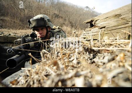 Us Marine Corps Lance Cpl. Mario Melendez, Flotte Antiterrorism Security Team Pacific zugeordnet, wacht als Mitsoldaten ein Graben klar in einem taktischen Bewegung Übung im Camp Rodriguez, Südkorea, am 1. März 2012. Marines auf den Antiterrorism Security Team im Camp Rodriguez Feuer Komplex während der Übung trainiert zugeordnet. Stockfoto