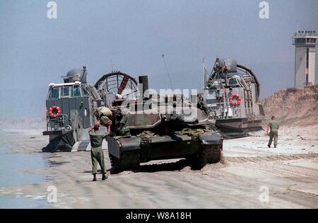 Der Fahrer des US Marine Corps M-1A1 Abrams Tank ist Boden geführt, als er grenzt an ein US-Marine Landing Craft Air Cushion, oder Lcac, wie es sitzt auf weißen Strand, Camp Pendleton, Calif., am 20. Juni 1997, während der Übung Kernel Blitz 97. Kernel Blitz 97 ist eine große amphibische Übung in Südkalifornien und in den Gewässern vor der Küste. Mehr als 12.000 Matrosen, Marines, Soldaten, Wachposten und Fliegern in der Übung, die entworfen ist, um die Navy-Marine Corps teamХs Fähigkeit Combat Power an Land zu Projekt beteiligt sind. Das lcac, vom Angriff Handwerk Einheit 5, die den Tank, Ladung und Stockfoto