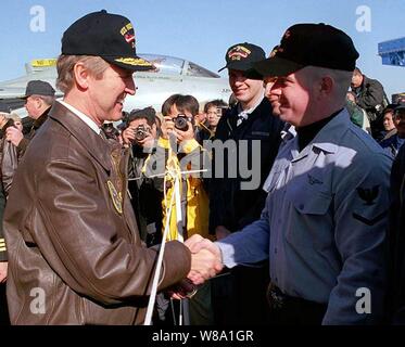 Verteidigungsminister William S. Cohen (links) schüttelt Hände mit Petty Officer 3rd Class Kevin Reed (rechts) auf dem Flugdeck der Flugzeugträger USS Independence (CV 62), während das Schiff in Yokosuka, Japan, Jan. 21, 1998 günstig ist. Cohen ist der Besuch des Schiffes an die Crew zu sprechen und die Bereitstellung der Unabhängigkeit Battle Group in den Persischen Golf verkünden die USS Nimitz Battle Group zu entlasten. Reed, ein Marine photographerХs mate, wird von Bar Harbor, Maine. Stockfoto