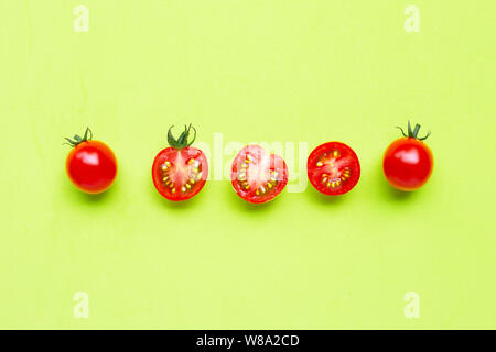 Frische Tomaten, ganze und halbe Schneiden auf grünem Hintergrund. Ansicht von oben Stockfoto