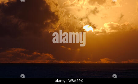 Sunrise durch Wolken über dem Wasser Stockfoto