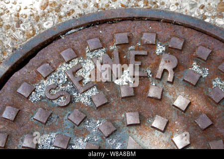 Ein rostiger Kanaldeckel mit Kanal angezeigt. Stockfoto