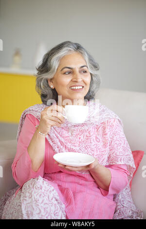 Ältere Frau trinkt Tee und Tag träumen Stockfoto