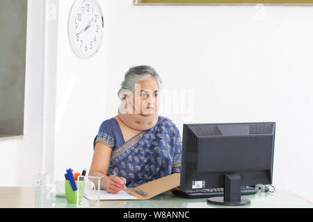 Geschäftsfrau trägt eine Nackenstütze und arbeitet in einem Büro Stockfoto