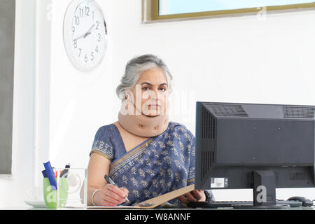 Geschäftsfrau trägt eine Nackenstütze und arbeitet in einem Büro Stockfoto