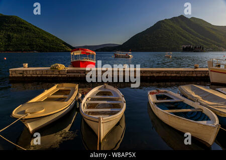 Einen malerischen Blick auf die Boote in der Postkarte perfekte Stadt Perast in Kotor Bucht bei Sonnenuntergang angedockt mit Bergen im Hintergrund im Sommer, Montenegro Stockfoto