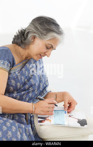 Ältere Frau, die Unterzeichnung eines Schecks Stockfoto