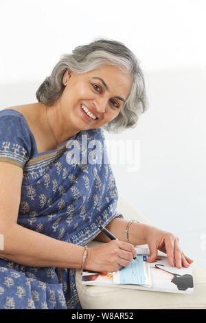 Ältere Frau, die Unterzeichnung eines Schecks Stockfoto