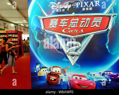 ---- Leute vorbei ein Poster von Film Pixars "Cars 2" von Disney während einer Buchmesse in Shanghai, China, 19. August 2011. Walt Disney Co hat Stockfoto