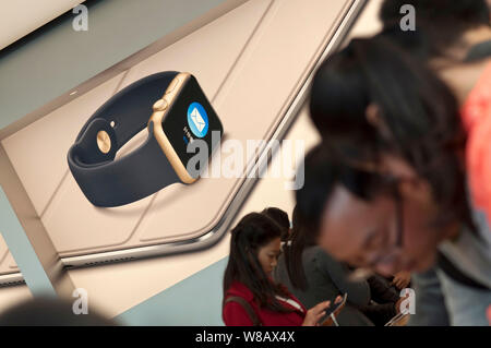 ------ Kunden versuchen, elektronische Produkte vor eine Werbung für die Apple Watch in einem Apple Store in der Stadt Guangzhou, Südchina Guan Stockfoto