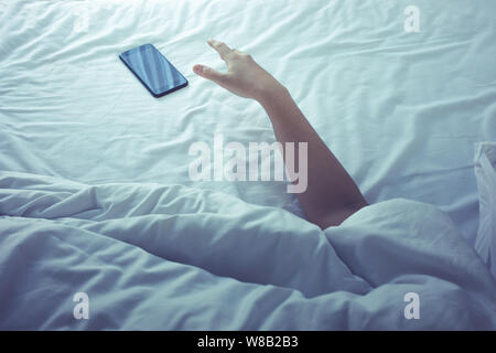 Junge Frau schlafend auf dem Bett mit Smartphone am Morgen. lifestyle Konzepte Ideen Stockfoto