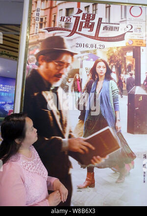 ---- Eine Chinesische filmgoer Spaziergänge hinter einem Plakat des Films "Buch der Liebe" in einem Kino in Yichang, Provinz Hubei, China 21. April 2016. Stockfoto